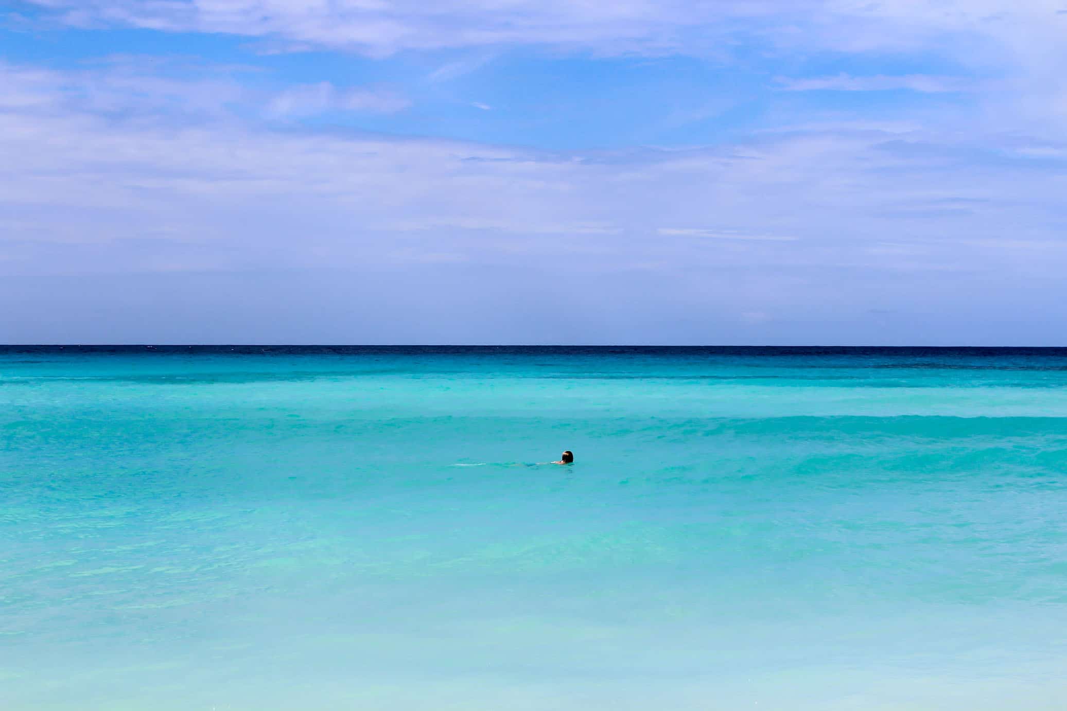 Sole swimmer in a big blue caribbean sea with a big blue sky Barbados